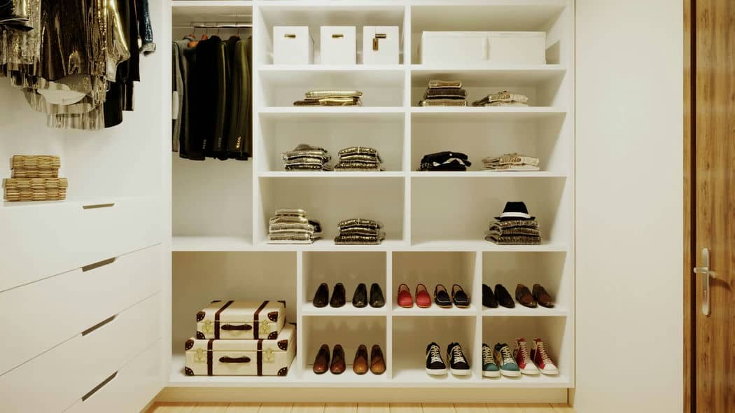 Um closet organizado com prateleiras contendo vários sapatos e bolsas.