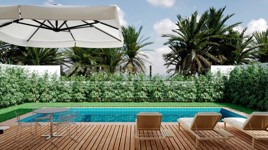 Casa térrea com área de estar ao ar livre sombreada por guarda-sol, próxima a uma piscina cercada por sebes.