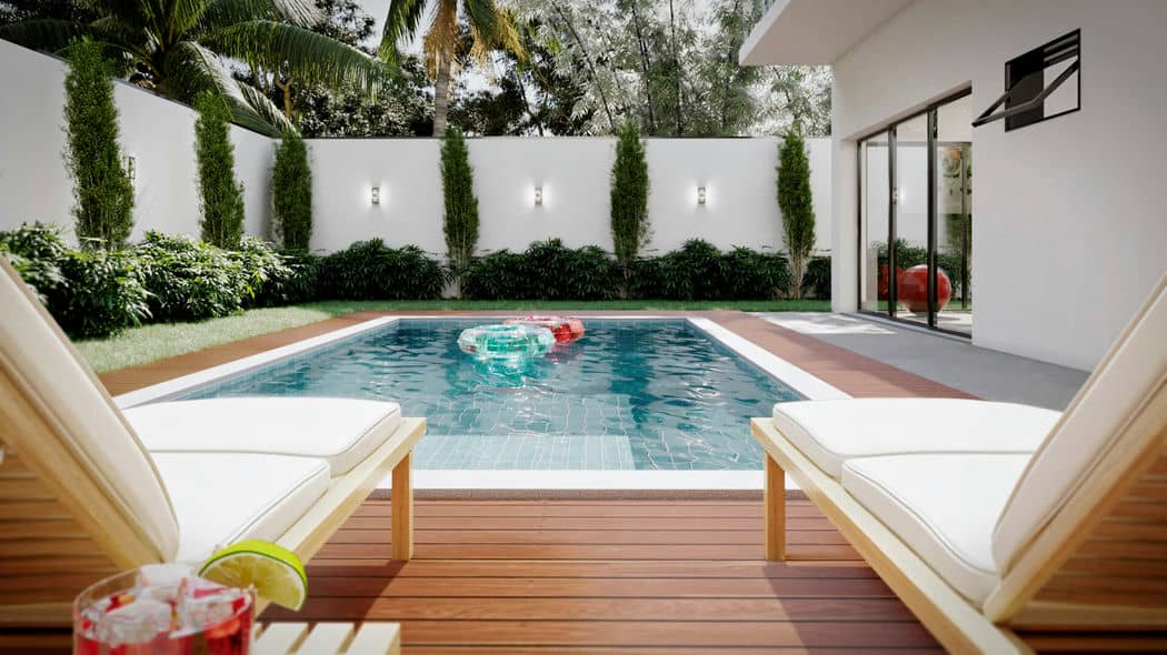 Área de piscina moderna cercada por paredes brancas e folhagem verde, com duas espreguiçadeiras em um deck de madeira e um brinquedo inflável flutuando na piscina.